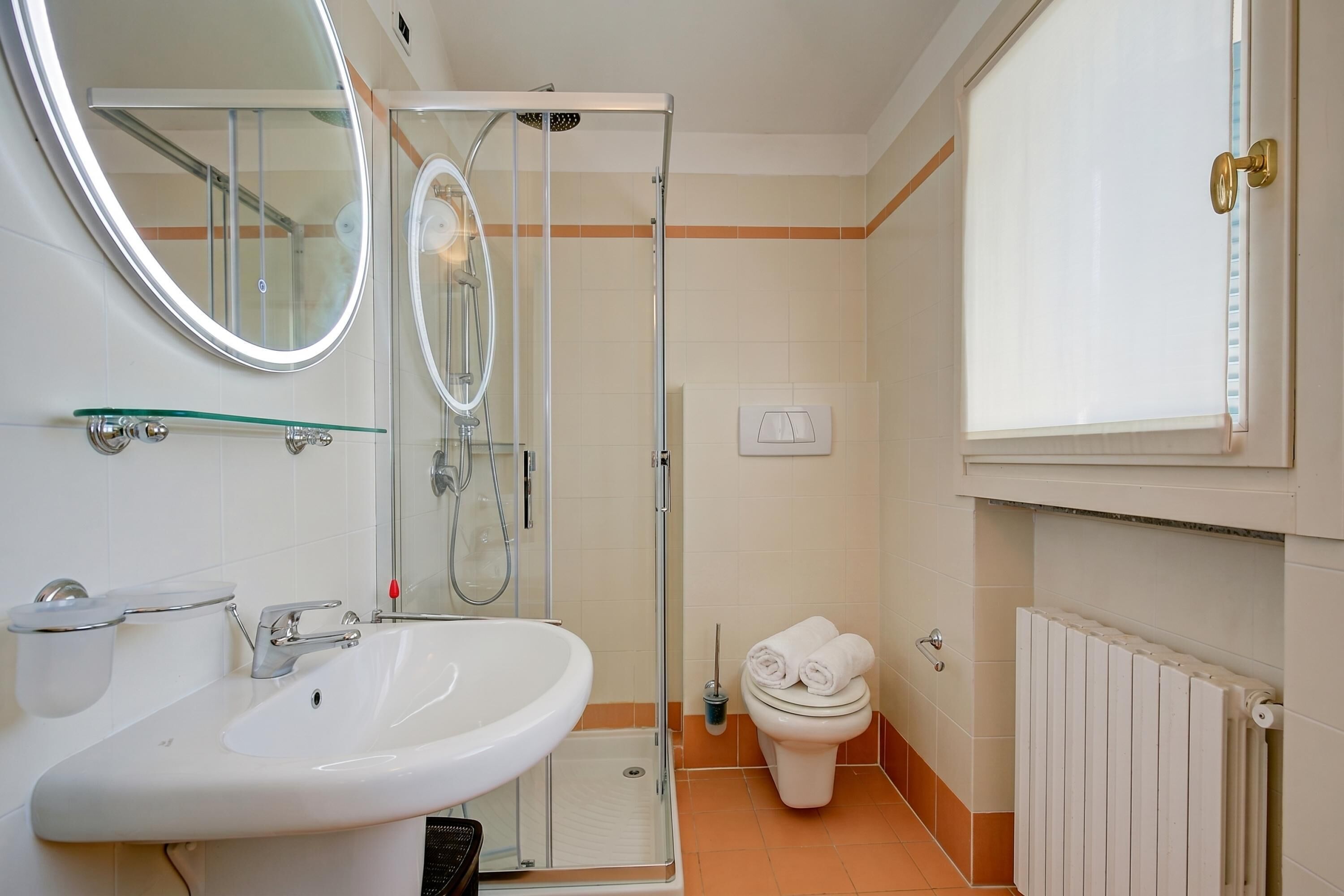 A bathroom with a sink, mirror, shower, toilet, and towel rack.
