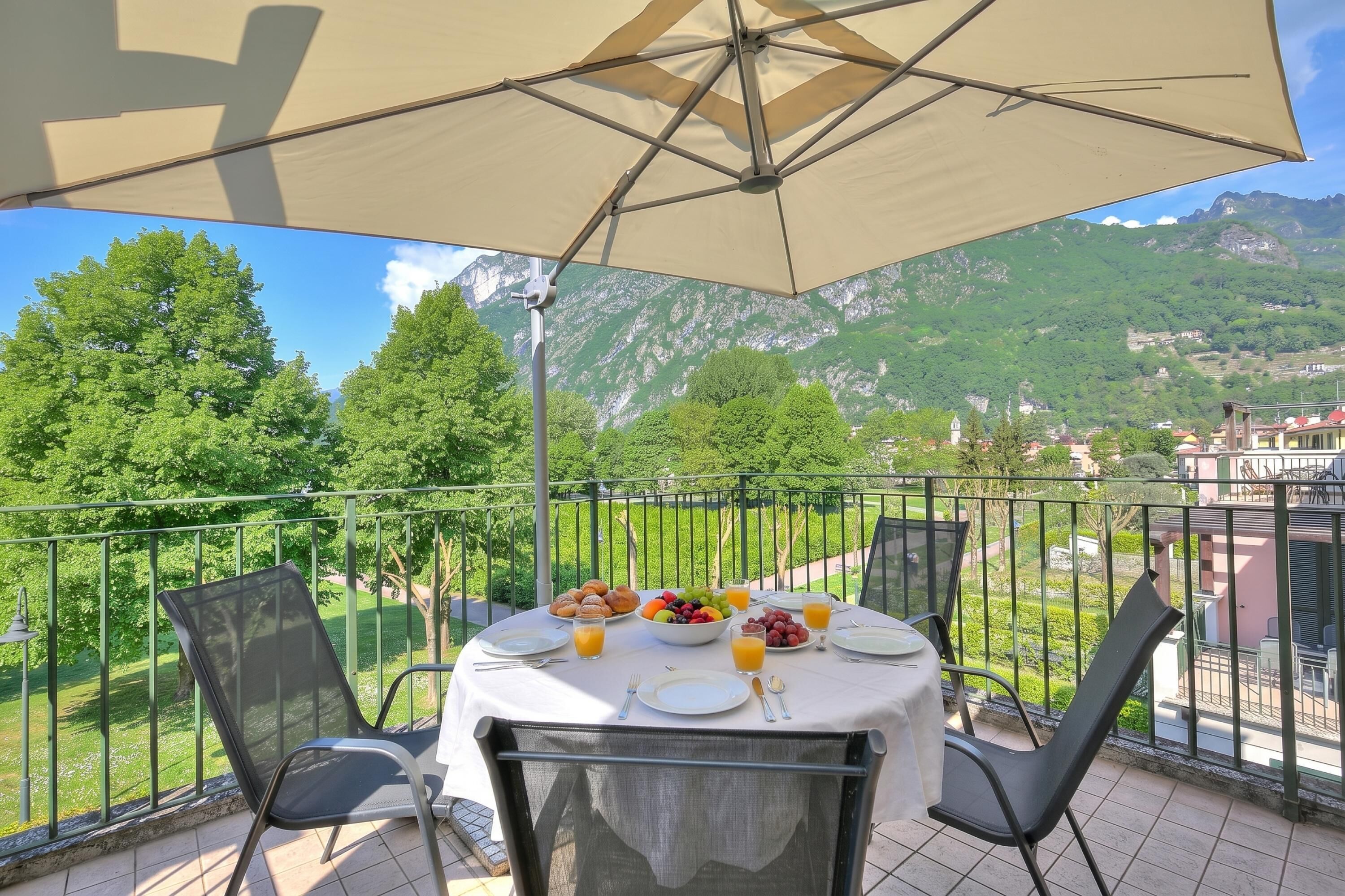 Un balcon avec une table préparée pour le petit-déjeuner, offrant une vue sur un paysage montagneux.