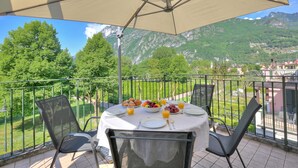 Un balcon avec une table préparée pour le petit-déjeuner, offrant une vue sur un paysage montagneux.