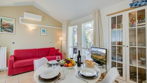Un coin repas avec une table dressée pour deux personnes, un canapé rouge et un meuble avec des portes en verre.