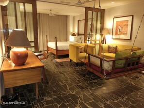 Una habitación de hotel con una cama, un sofá, un escritorio y una lámpara de pie.