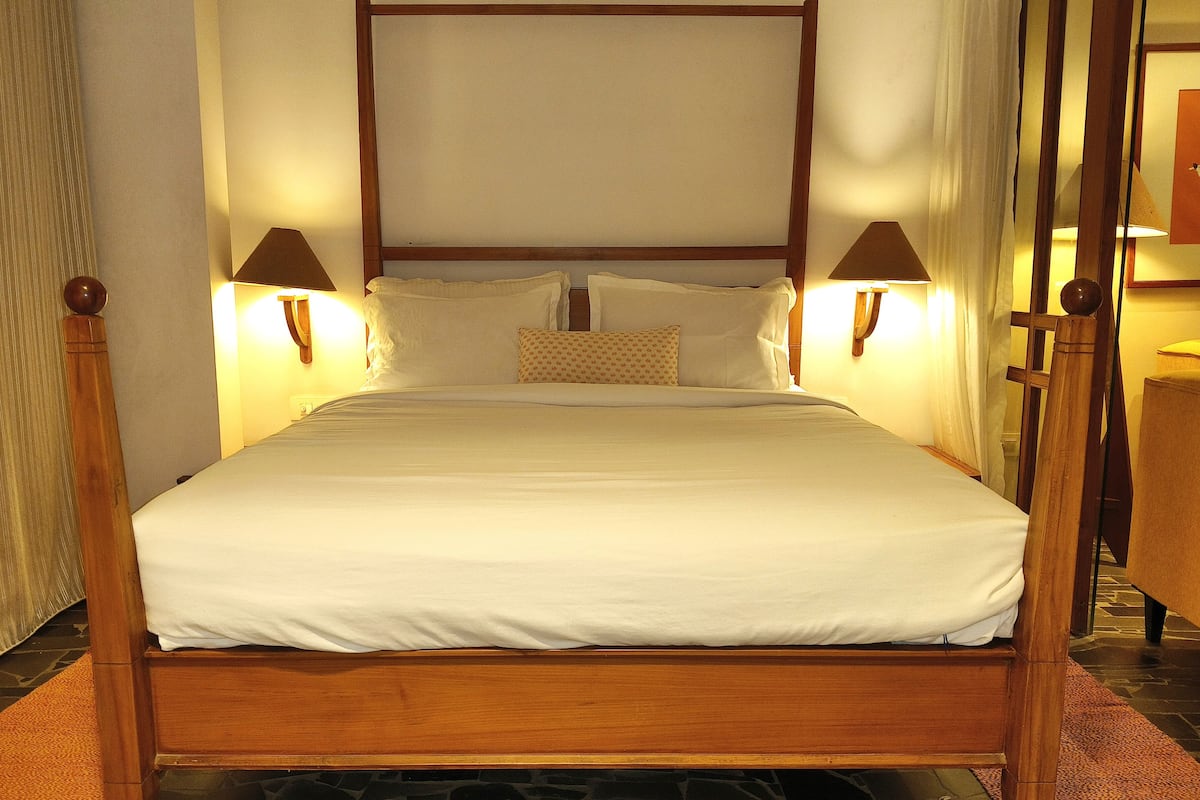 A neatly made bed with white linens, two bedside lamps, and a wooden headboard.