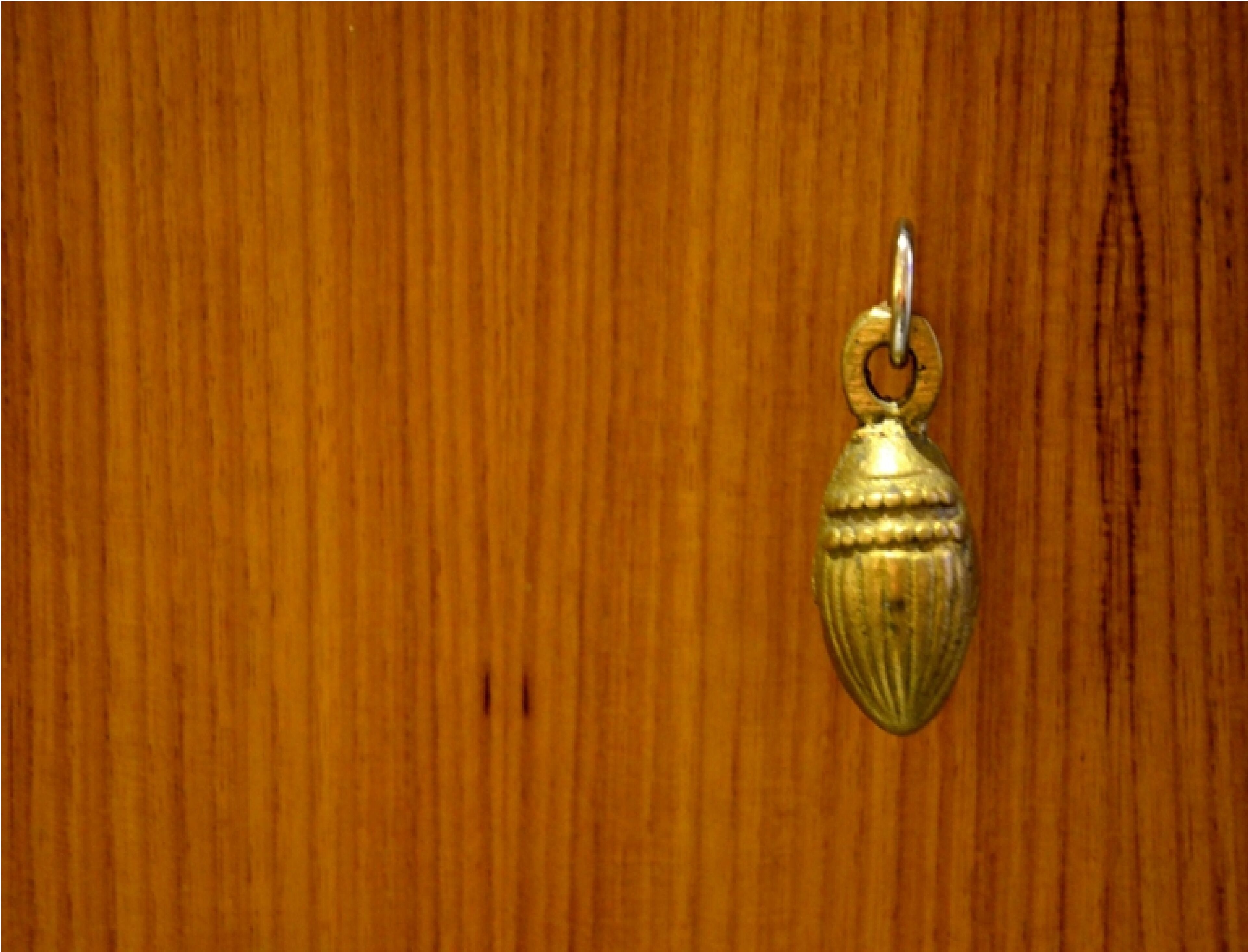 Ein Schlüsselanhänger aus Messing vor Holz.