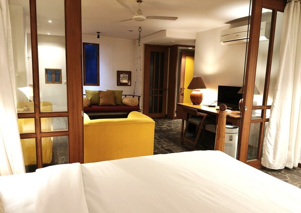 Ein Hotelzimmer mit einem Bett, einem Schreibtisch mit Lampe, einem Sessel und einem Fernseher.