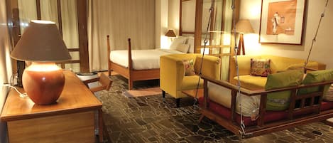 A hotel room with a bed, a sofa, a desk, and a standing lamp.