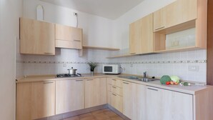 A modern kitchen with light wood cabinets, a microwave, and a sink.