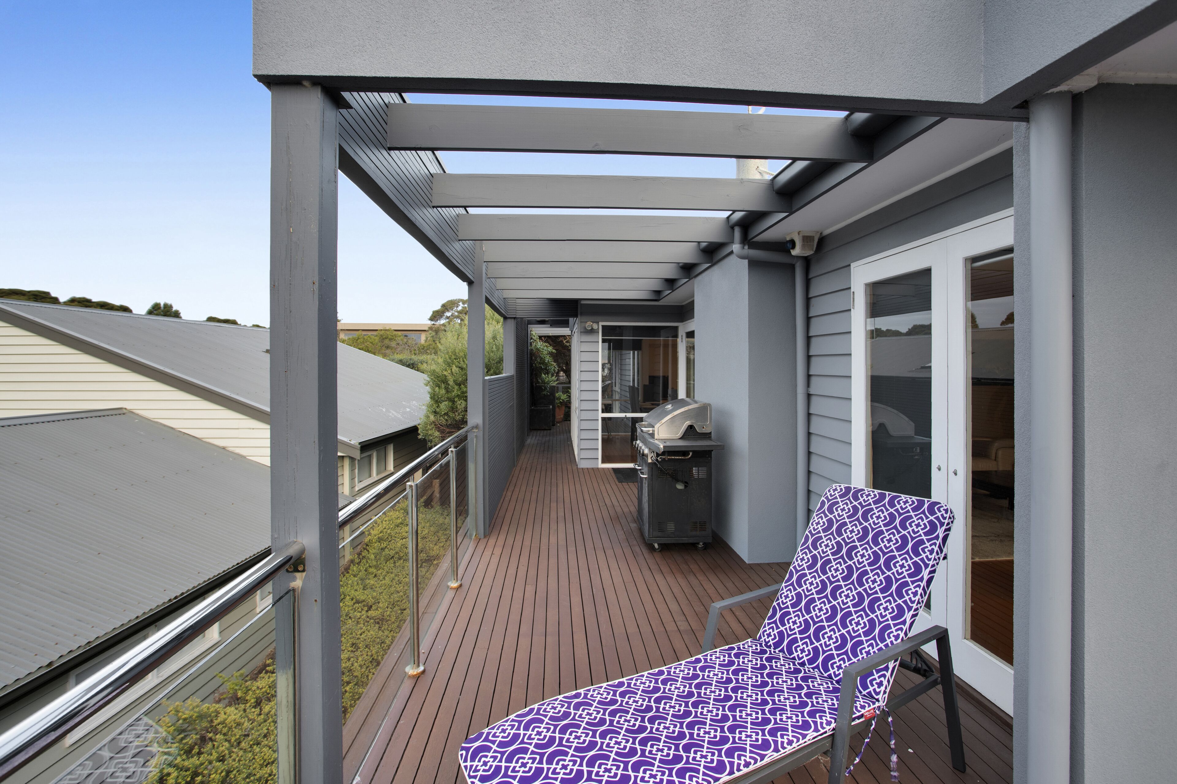 Un balcon abrité, équipé d’un barbecue, d’un fauteuil de relaxation et offrant une vue sur le quartier.