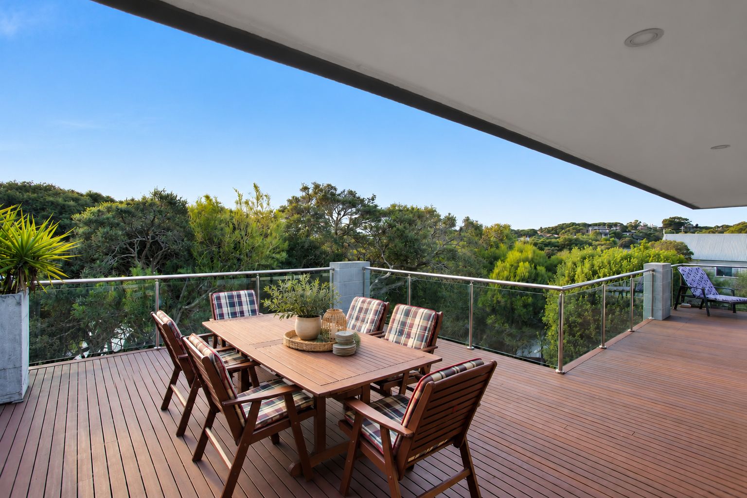 Une terrasse en bois avec une table et des chaises, offrant une vue sur un paysage magnifique.