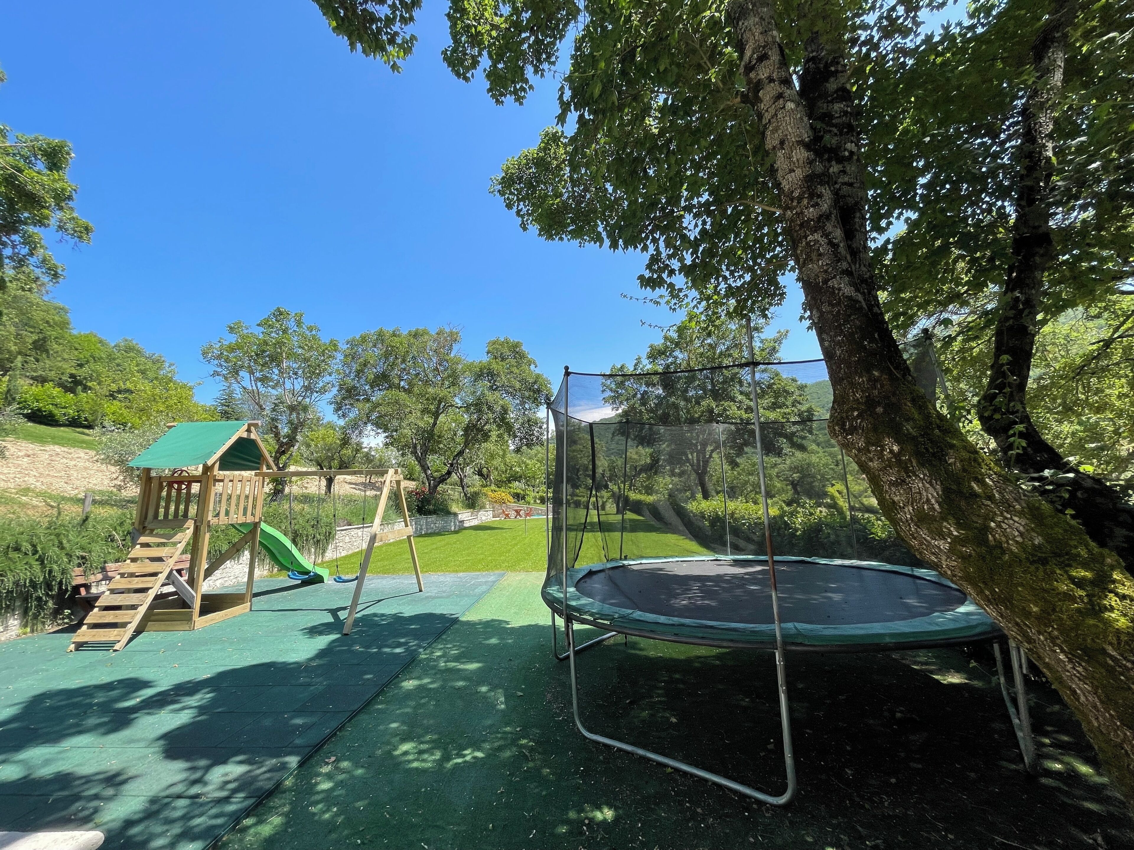 A playground with a slide, swing set, and trampoline.