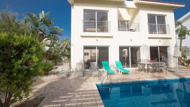 A two-story building with a swimming pool, outdoor seating, and a patio area. - Protaras Delfini Villa Dv5 (Protaras)