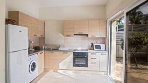 A modern kitchen with wooden cabinets, a built-in oven, a washing machine, and a microwave. - Protaras Delfini Villa Dv5 (Protaras)