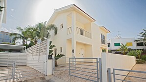 A two-story building with a gated entrance, a balcony on the upper floor, and a clear sky. - Protaras Delfini Villa Dv5 (Protaras)