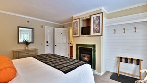 Un dormitorio con cama, cómoda, espejo, chimenea y perchero.