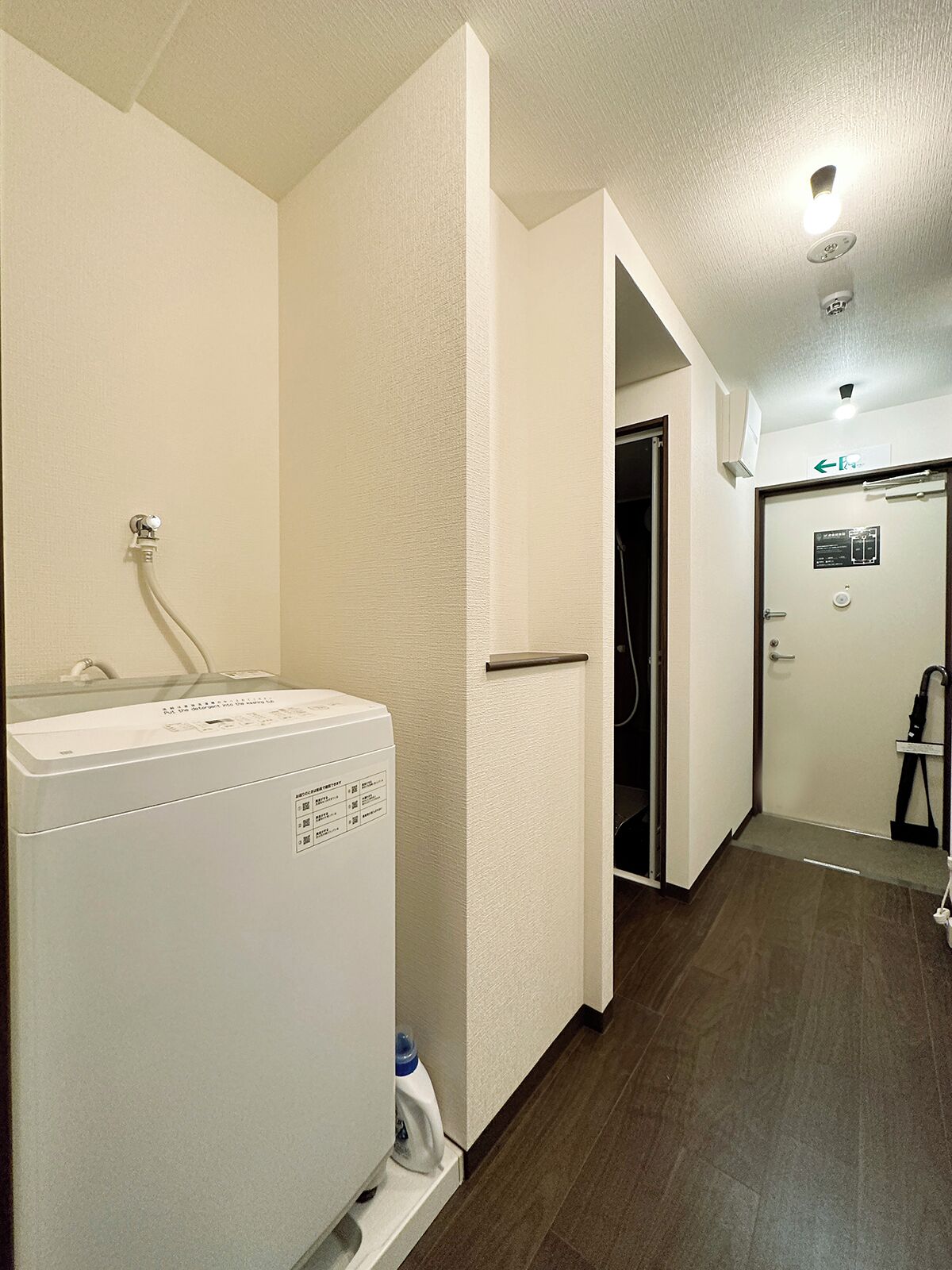 A laundry area with a washing machine, a water heater, and a door leading to a bathroom.