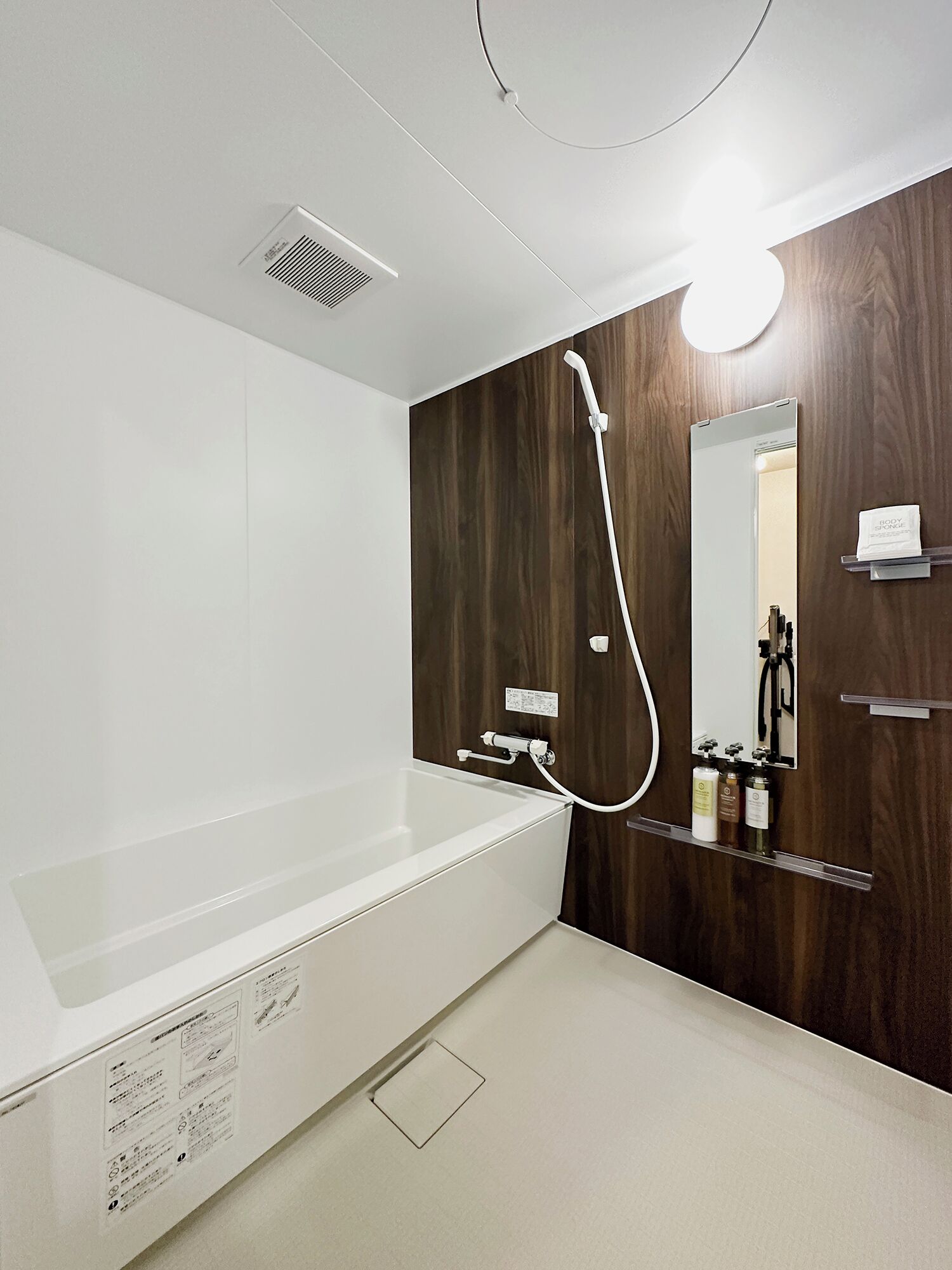 A modern bathroom with a bathtub, a shower, a mirror, and a shelf with toiletries.