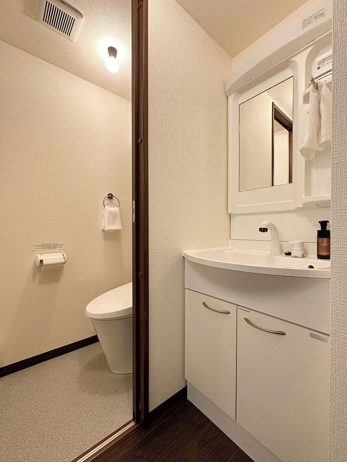 A bathroom with a toilet, a sink, a mirror, and a shower area.
