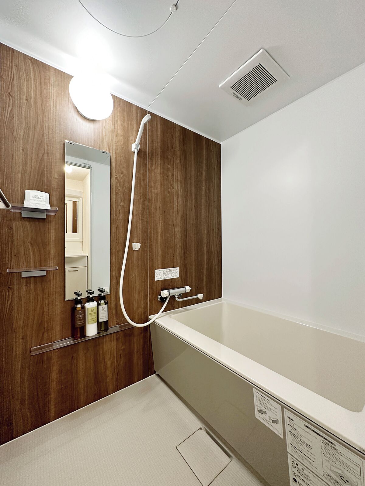 Un baño moderno con tocador de madera, un espejo grande y una bañera.