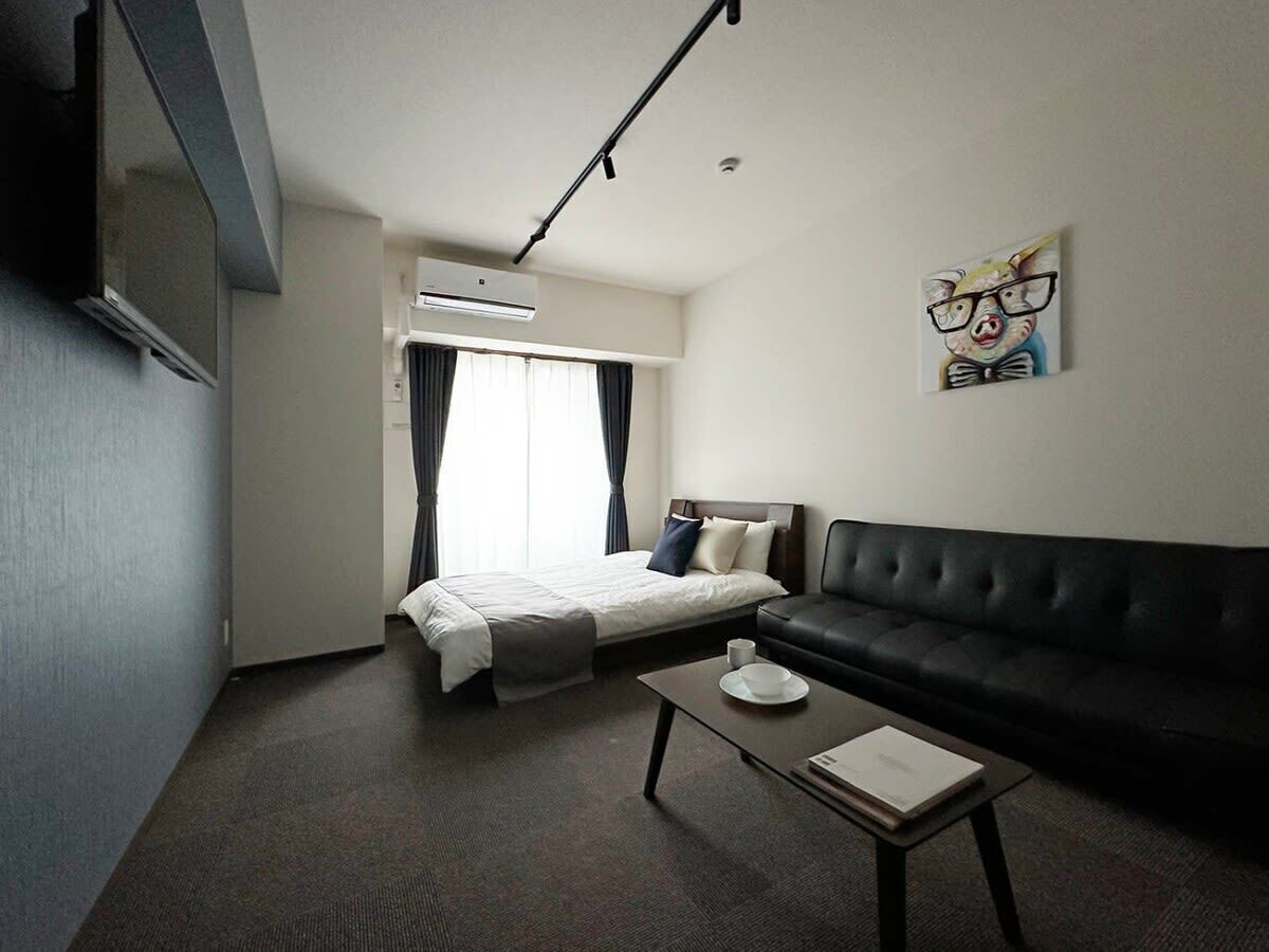 A hotel room with a bed, a sofa, a coffee table, and a painting on the wall.