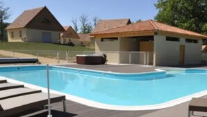 Una piscina con muelle de madera y sillas de descanso.