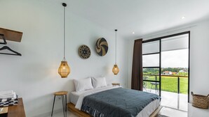 Une chambre moderne avec un grand lit, un banc en bois, un petit tabouret et une vue sur l’extérieur.