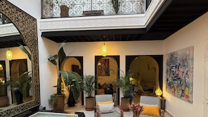 A luxurious indoor pool area with a high ceiling, ornate railings, and multiple seating areas with patterned cushions. - Magnificent Riad Julilu Privatise in the heart of the Medina (11P) (Marrakech)
