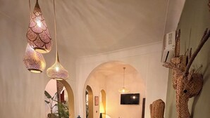 A dining area with a wooden table, woven chairs, and hanging pendant lights. - Magnificent Riad Julilu Privatise in the heart of the Medina (11P) (Marrakech)