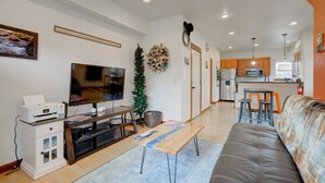 A modern living room with a flat-screen TV, a coffee table, and a sofa.