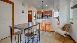 A modern kitchen with wooden cabinets, a stainless steel refrigerator, and a bar area with stools.