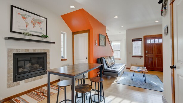 A modern kitchen with a fireplace, a dining table with stools, and a cozy seating area with a sofa and a coffee table.