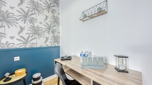 A room with a wooden desk, a chair, a shelf with plants, a water bottle, and a clock. - House 8 persons - Subway + train station / Private parking lot / Wifi / CDG airport / (La Courneuve)