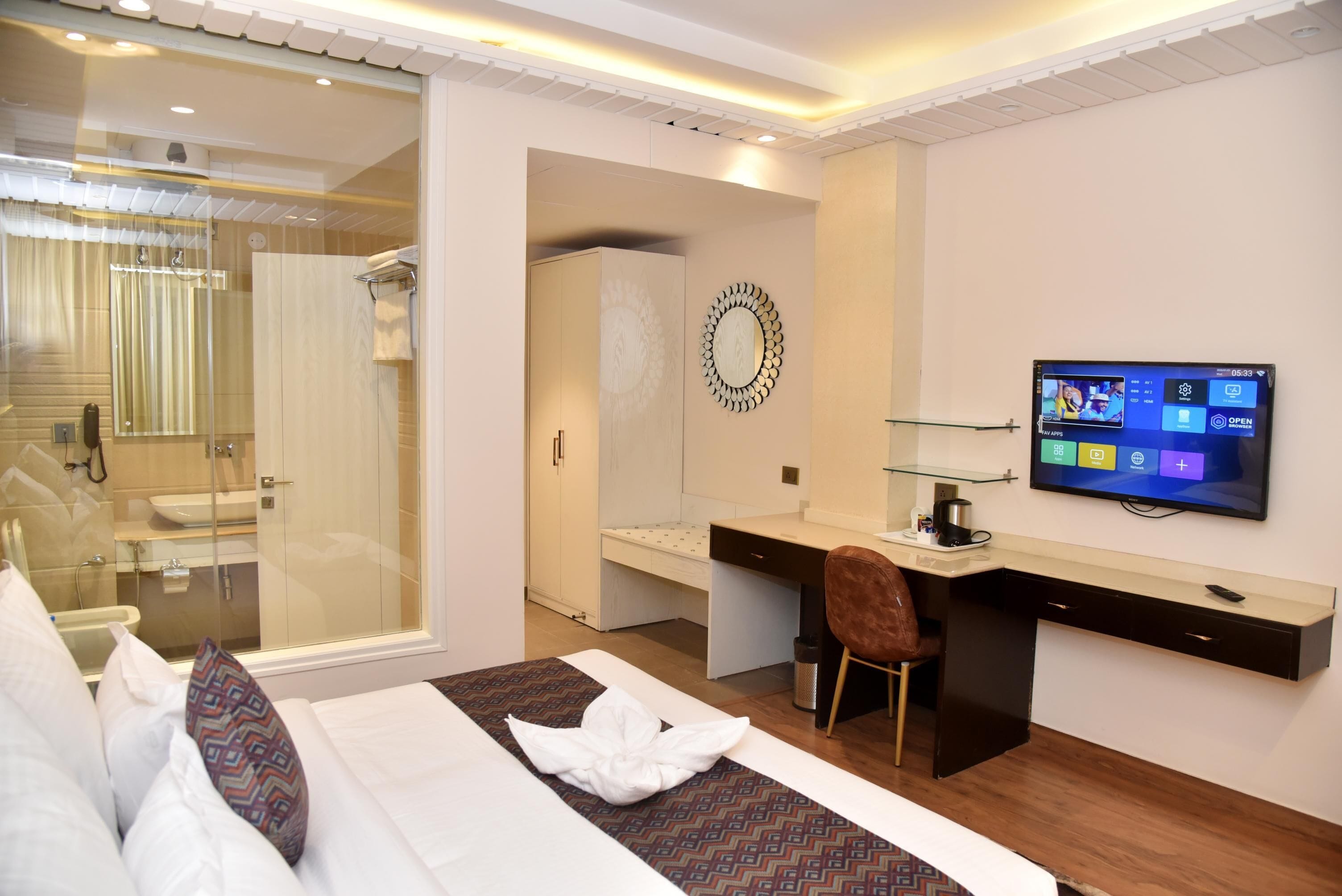 Una habitación de hotel moderna con cama, escritorio, televisión y zona de ducha.