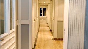 Un pasillo largo y estrecho con paredes blancas y suelo de madera.