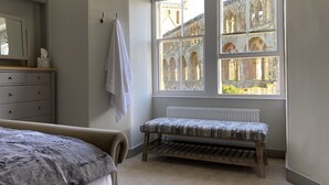 A bedroom with a large window, a radiator, a wooden bench, and a dresser. - Abbey House, charming traditional historic house. Spectacular views of the Abbey (Jedburgh)