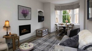 A cozy living room with a fireplace, a dining area with a view of greenery, and a comfortable seating area. - Abbey House, charming traditional historic house. Spectacular views of the Abbey (Jedburgh)
