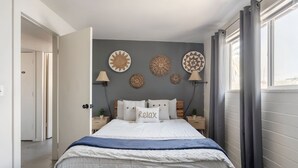 A bedroom with a bed, bedside tables, wall decor, and a window with curtains. - Bright 4BR Getaway – Yard & Perfect Group Escape! (Tucson)
