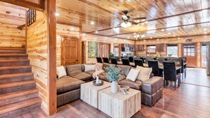 Un intérieur spacieux de chalet en bois, comprenant un salon, un coin repas et une cuisine.