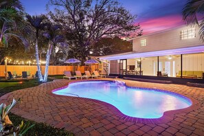 A swimming pool with a brick border, surrounded by lounge chairs and umbrellas. - 5BR Tropical Beach Villa! Heated Pool House (Seminole)
