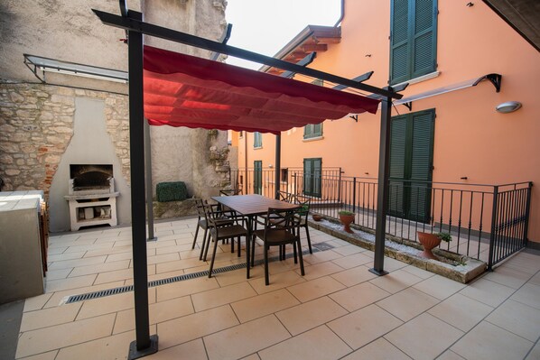 An outdoor patio with a table and chairs, a red canopy, and a stone fireplace.