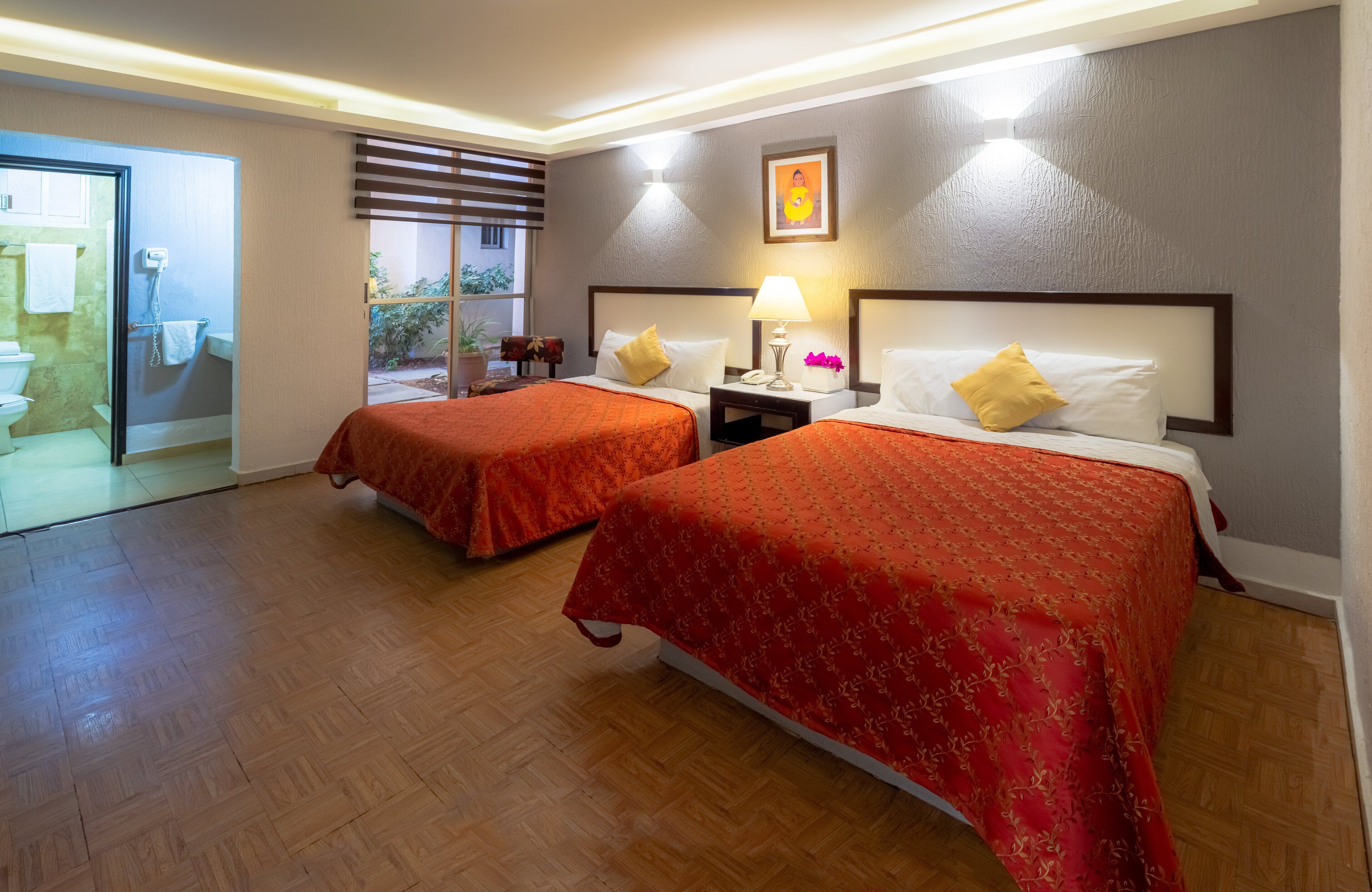 A hotel room with two beds, a bathroom, and a view of the outside.