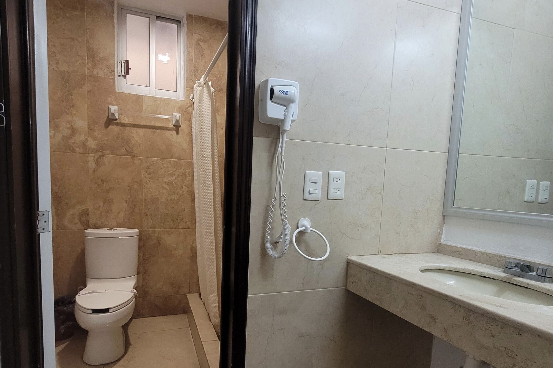 A bathroom with a toilet, a shower, a sink, and a mirror.