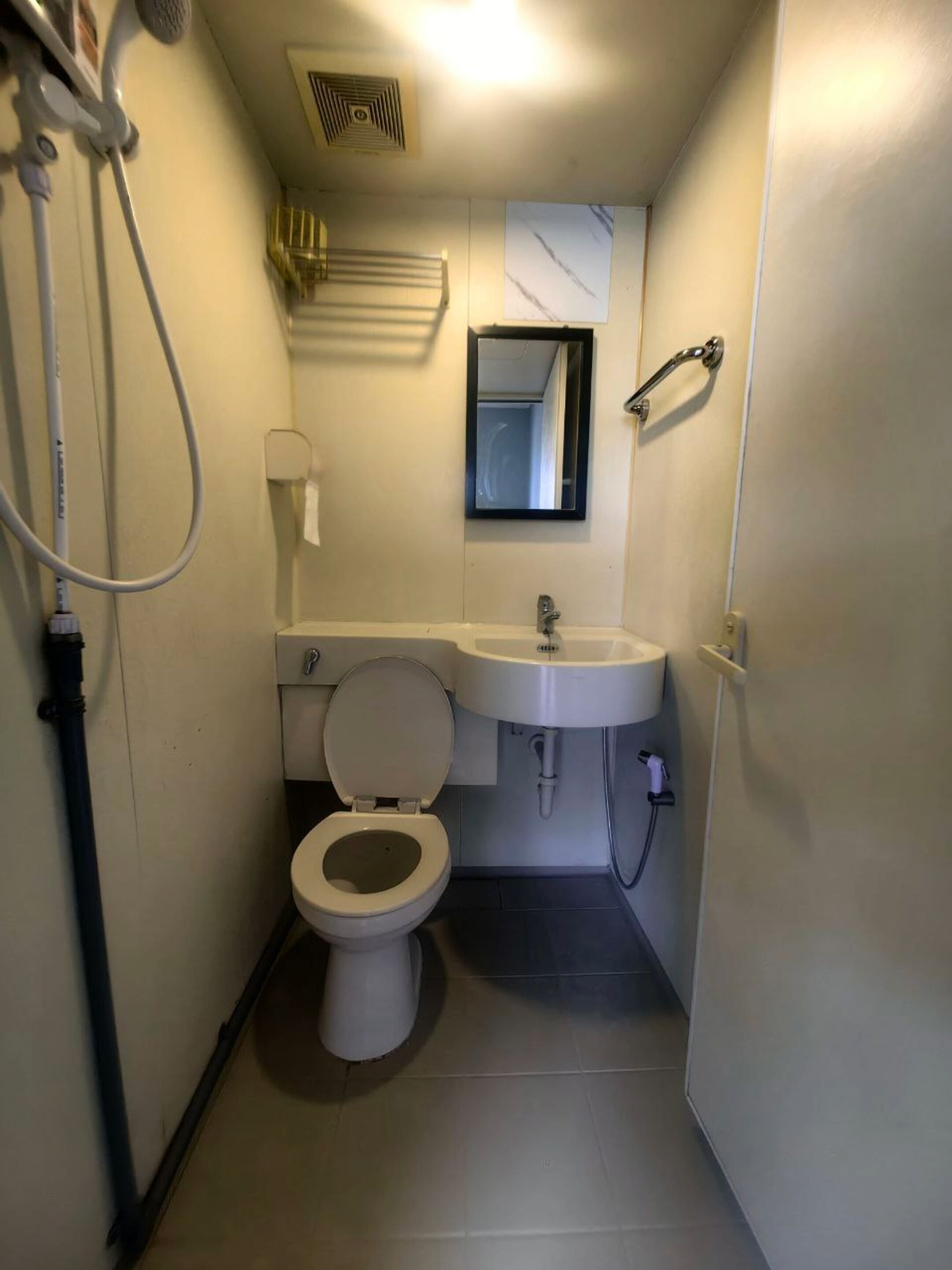 A small, compact bathroom with a toilet, sink, and shower.