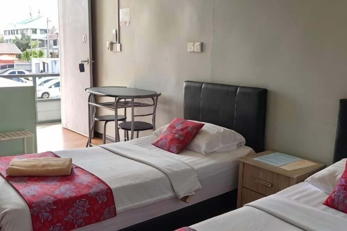 A hotel room with two beds, a small table, and a chair.
