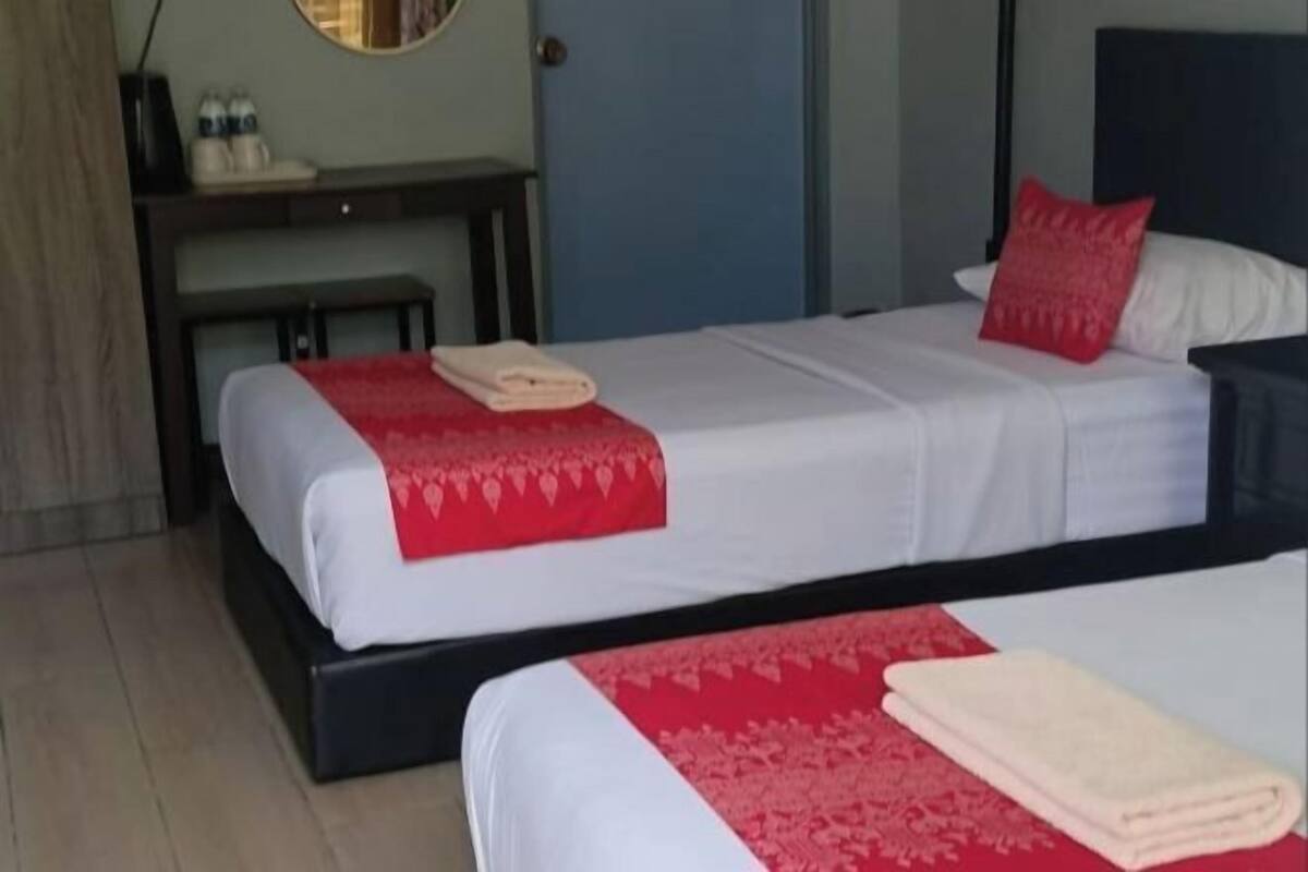 A hotel room with two beds, a desk, and a mirror.