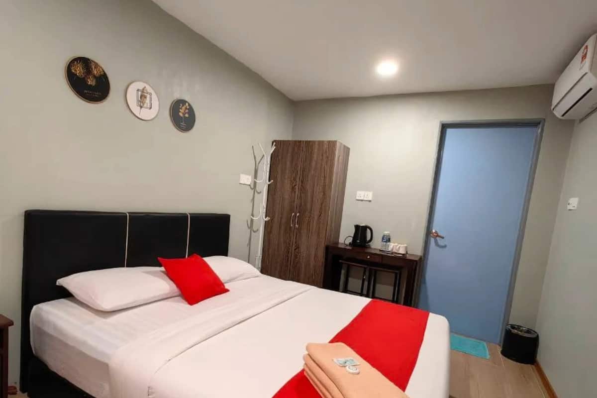 A hotel room with a bed, a wardrobe, a desk, and a door.