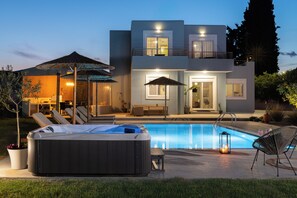 A modern two-story house with a swimming pool, hot tub, and outdoor seating area.