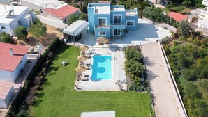 A multi-story house with a swimming pool, surrounded by a well-maintained lawn and a few trees. - Ethria Pool Villa with heated jacuzzi (Αφάντου)