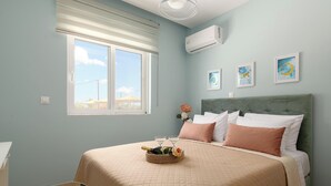 A bedroom with a bed, a window, an air conditioner, and wall art. - Ethria Pool Villa with heated jacuzzi (Αφάντου)