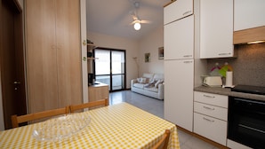 Eine kleine Küche mit Esstisch, Schränken und Deckenventilator.