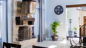 A modern living room with a stone fireplace, a flat-screen TV, a clock, and potted plants. - Large Modern home nestled in Alvarado! Hot Tub & Theater (Alvarado)