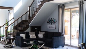 A modern living room with a staircase, a sofa set, a coffee table, and a view of the outdoors. - Large Modern home nestled in Alvarado! Hot Tub & Theater (Alvarado)